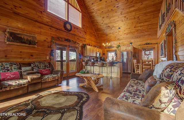 living room with dark wood-type flooring, wooden ceiling, an inviting chandelier, high vaulted ceiling, and wood walls