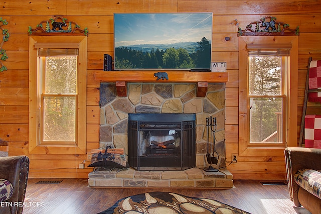 room details with hardwood / wood-style flooring, wood walls, and a stone fireplace