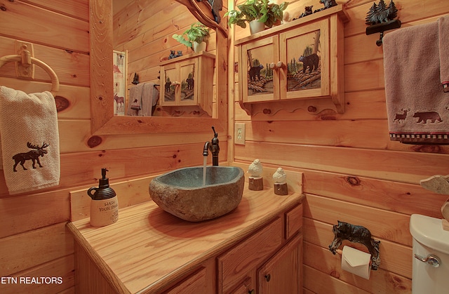 bathroom with wood walls, vanity, and toilet