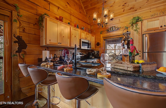 kitchen with light brown cabinetry, a breakfast bar, stainless steel appliances, vaulted ceiling, and pendant lighting