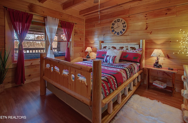 bedroom with beam ceiling, wood walls, and wood-type flooring