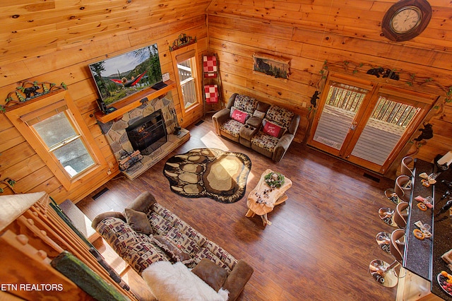 living room with wood ceiling, vaulted ceiling, wood-type flooring, a fireplace, and wood walls