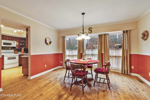 dining room with crown molding, light hardwood / wood-style flooring, and a healthy amount of sunlight