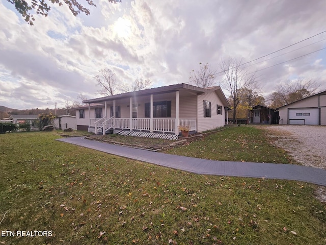 view of front of house featuring covered porch, a front lawn, and a garage