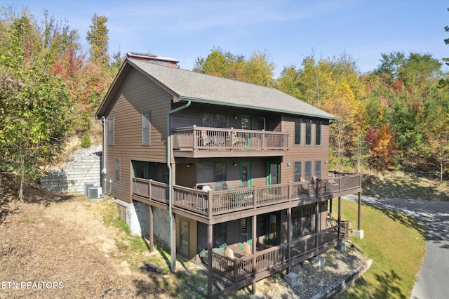 rear view of property with central air condition unit, a wooden deck, and a balcony