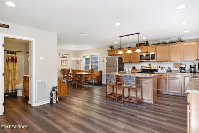 kitchen featuring a kitchen island, dark hardwood / wood-style floors, hanging light fixtures, a notable chandelier, and appliances with stainless steel finishes