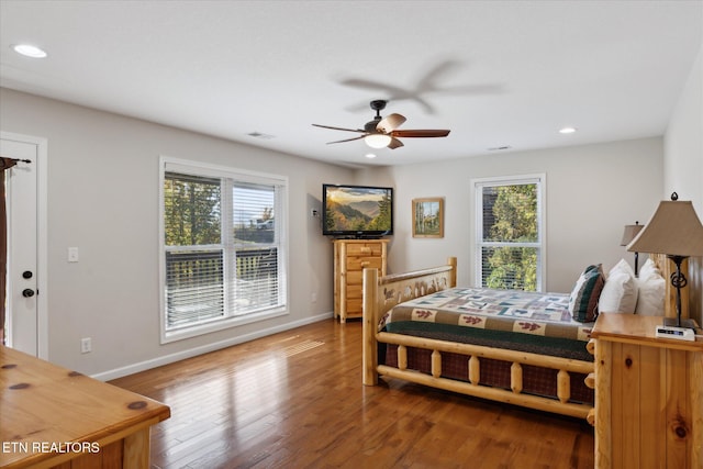 bedroom with ceiling fan, hardwood / wood-style flooring, and multiple windows