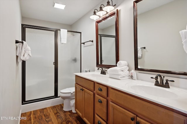 bathroom featuring a shower with door, vanity, hardwood / wood-style floors, and toilet