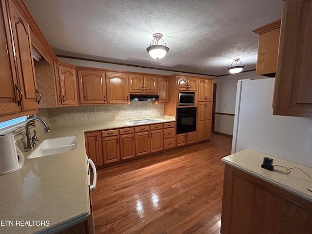 kitchen with decorative backsplash, a textured ceiling, light hardwood / wood-style flooring, black appliances, and sink