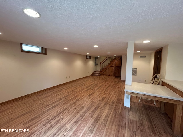 basement with hardwood / wood-style floors and a textured ceiling