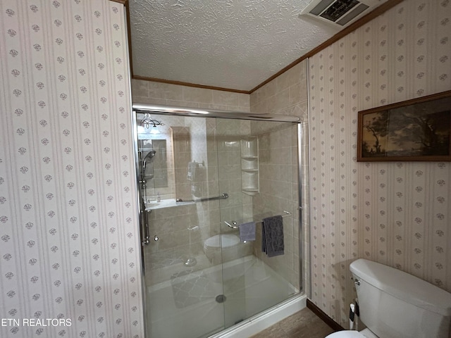 bathroom with crown molding, a shower with shower door, a textured ceiling, and toilet