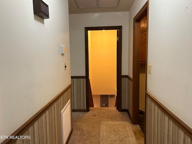 hall with a textured ceiling and light colored carpet