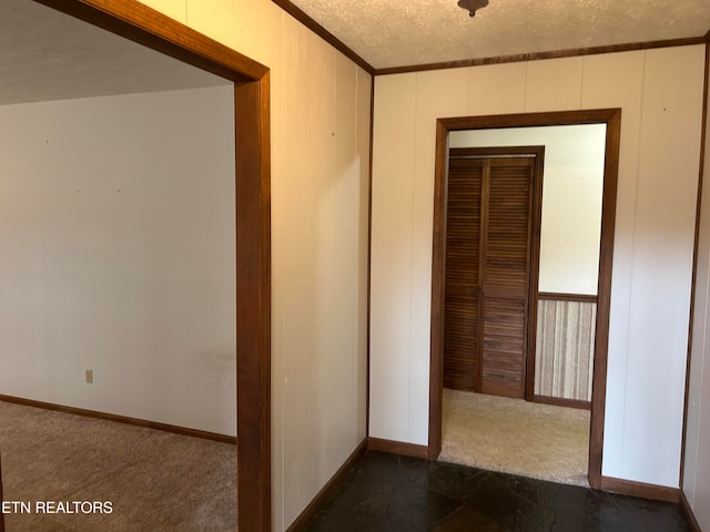 corridor featuring dark colored carpet and a textured ceiling