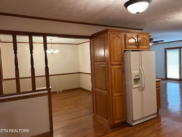 kitchen with white fridge with ice dispenser, a textured ceiling, pendant lighting, crown molding, and hardwood / wood-style flooring