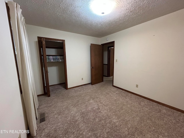 unfurnished bedroom with light carpet, a closet, and a textured ceiling