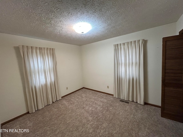 unfurnished room featuring a textured ceiling and carpet flooring