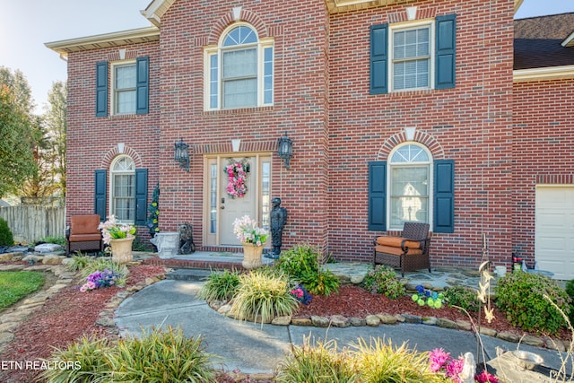 view of front of property with a garage, brick siding, and fence