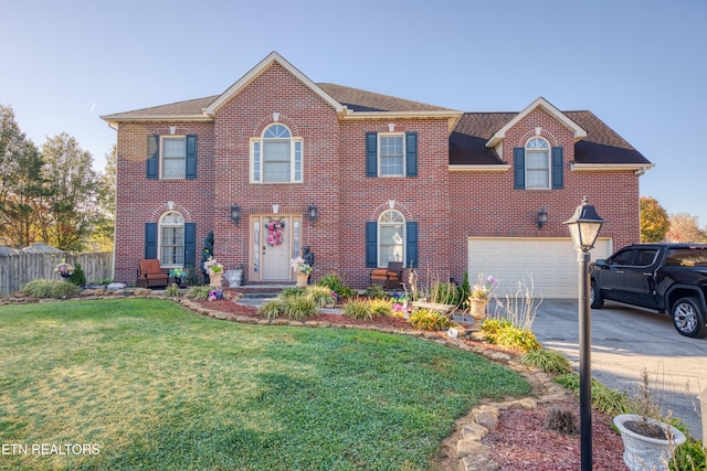 view of front of home featuring brick siding, fence, driveway, and a front lawn