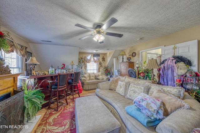 living room featuring light hardwood / wood-style floors, a healthy amount of sunlight, a textured ceiling, and ceiling fan