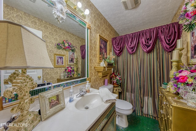 bathroom with vanity, toilet, and a textured ceiling