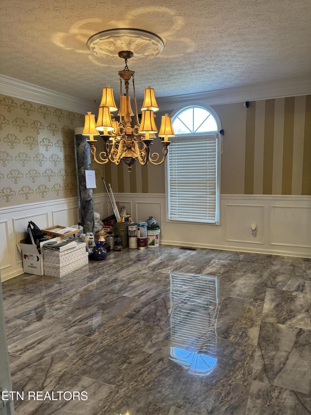 unfurnished dining area with a wainscoted wall, a textured ceiling, and wallpapered walls