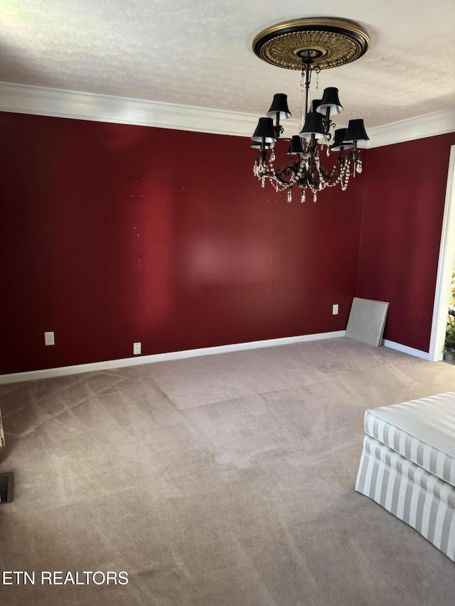 carpeted spare room with an inviting chandelier, a textured ceiling, visible vents, and crown molding