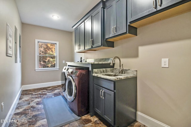 clothes washing area featuring sink, washing machine and dryer, and cabinets