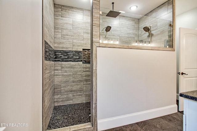 bathroom with vanity, a tile shower, and tile patterned flooring