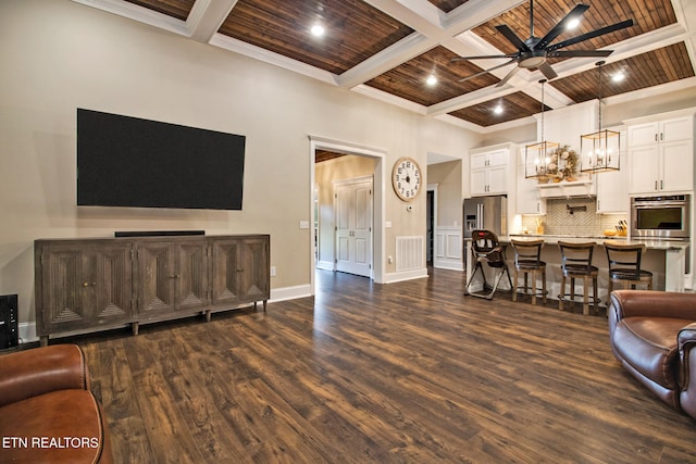 living room featuring beam ceiling, dark wood-type flooring, wooden ceiling, crown molding, and ceiling fan with notable chandelier