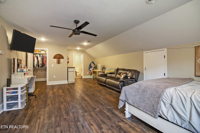 bedroom featuring lofted ceiling, a closet, dark wood-type flooring, a walk in closet, and ceiling fan