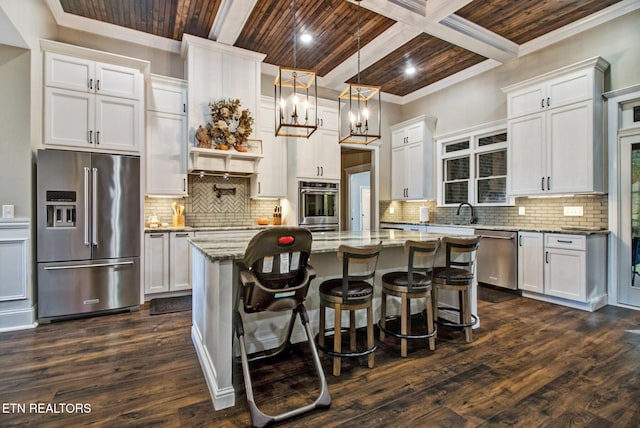 kitchen featuring appliances with stainless steel finishes, pendant lighting, a kitchen island, and white cabinets