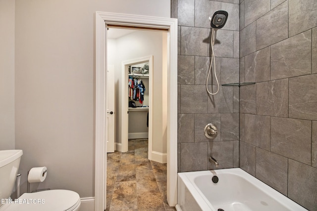 bathroom with toilet and tiled shower / bath