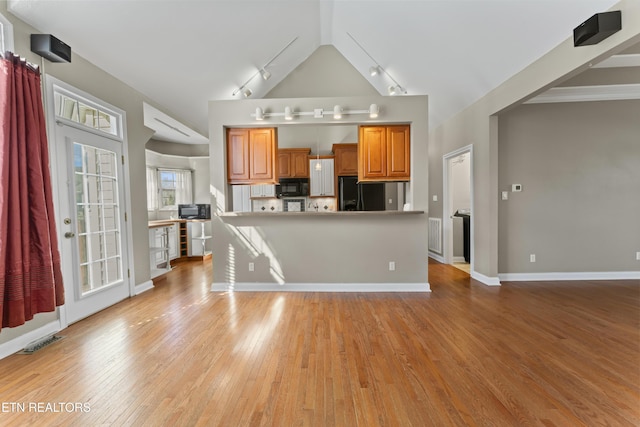 kitchen featuring black appliances, vaulted ceiling, and light hardwood / wood-style flooring