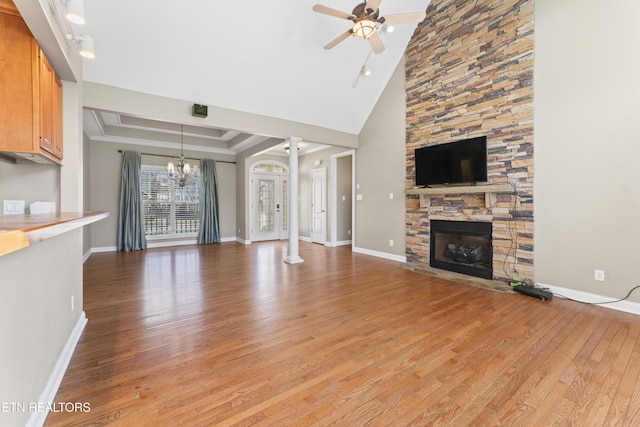 unfurnished living room with ceiling fan with notable chandelier, a fireplace, light hardwood / wood-style flooring, and high vaulted ceiling