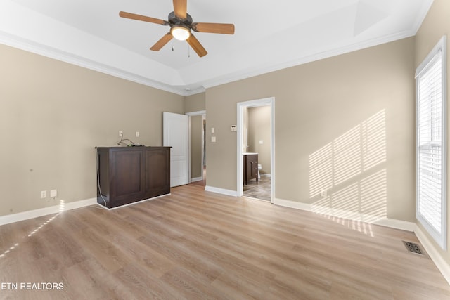 unfurnished room with a raised ceiling, light wood-type flooring, and a wealth of natural light