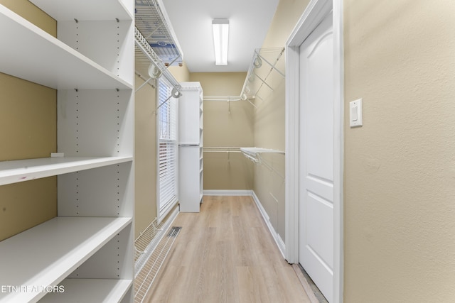 walk in closet with light hardwood / wood-style flooring