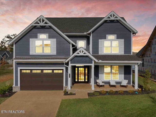 view of front of home featuring a lawn, a porch, and a garage