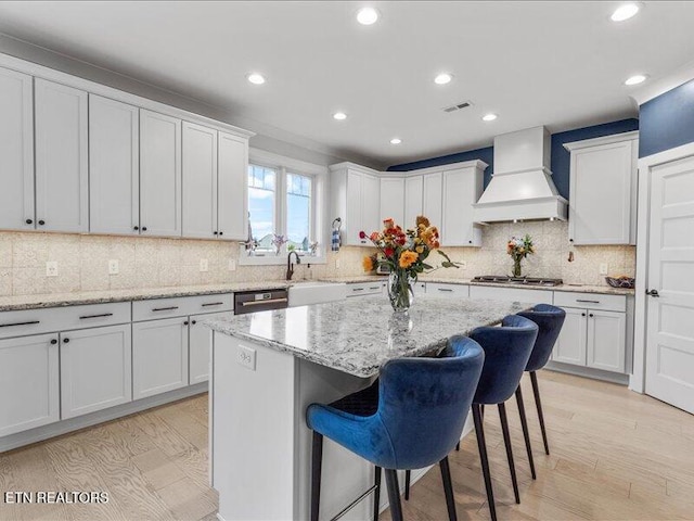 318 Buckhorn Way, Loudon, TN 37774 - kitchen featuring custom exhaust hood, light wood finished floors, a breakfast bar area, stainless steel appliances, and a kitchen island