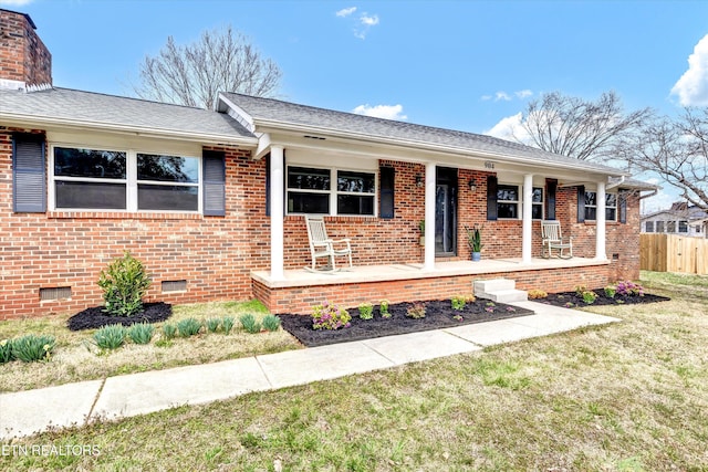 ranch-style home with brick siding, fence, a front yard, covered porch, and crawl space