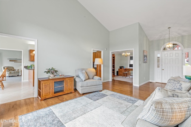 living room featuring high vaulted ceiling, light hardwood / wood-style floors, and a chandelier