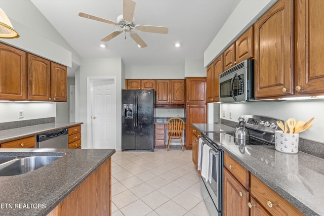 kitchen featuring stainless steel appliances, ceiling fan, light tile patterned floors, dark stone countertops, and lofted ceiling