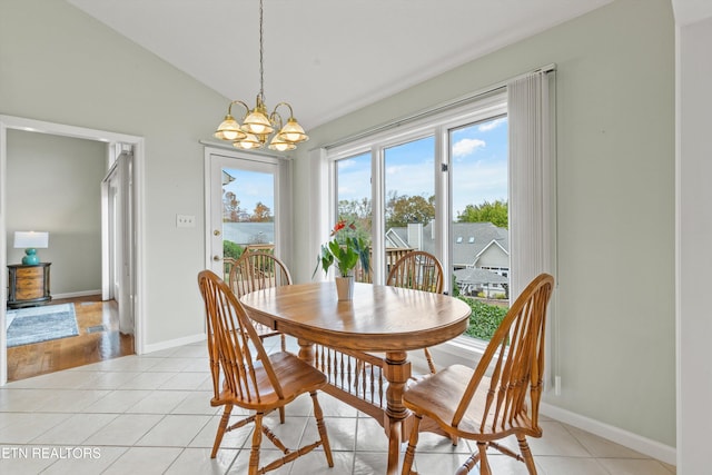 dining space featuring light tile patterned flooring, vaulted ceiling, and a chandelier