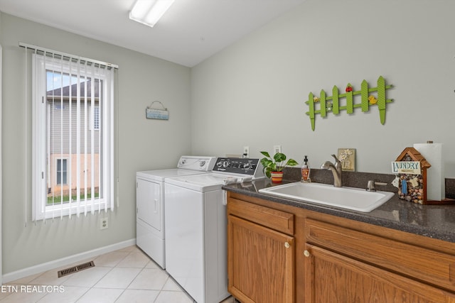 laundry room featuring washing machine and clothes dryer, a healthy amount of sunlight, sink, and light tile patterned floors