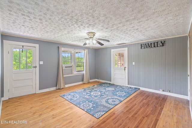 foyer entrance featuring ceiling fan, cooling unit, wood-type flooring, a textured ceiling, and wood walls