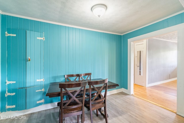 dining room featuring crown molding, wood-type flooring, and a textured ceiling