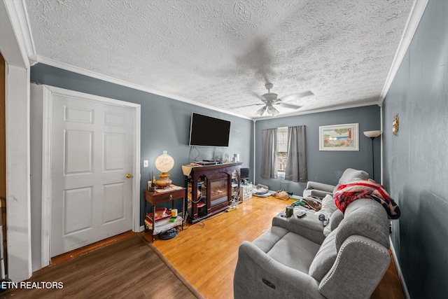 living room with ornamental molding, dark wood-type flooring, a fireplace, and ceiling fan