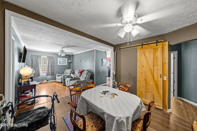 dining area featuring a textured ceiling, a barn door, and hardwood / wood-style flooring