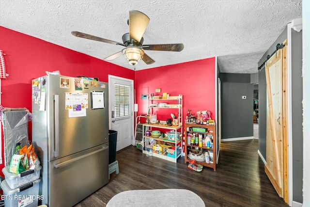 kitchen with stainless steel fridge, a barn door, ceiling fan, and dark hardwood / wood-style flooring