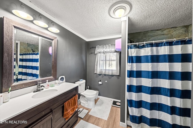 bathroom featuring hardwood / wood-style floors, a textured ceiling, toilet, ornamental molding, and vanity