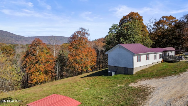 exterior space featuring a lawn, a mountain view, and central AC